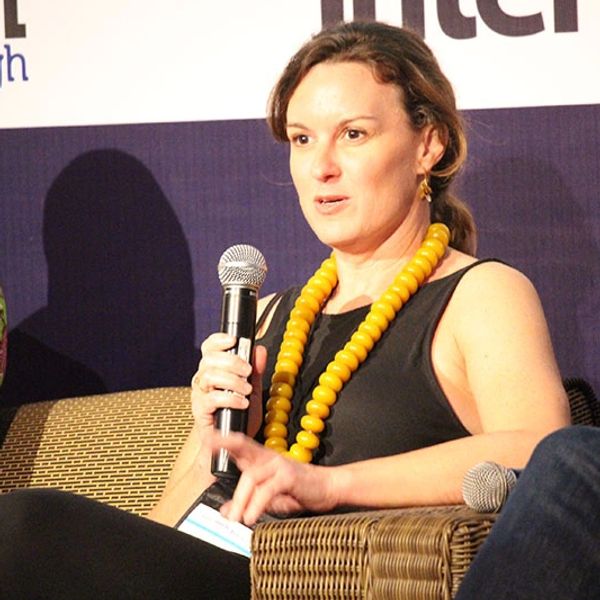 Woman speaking at a panel with a microphone.