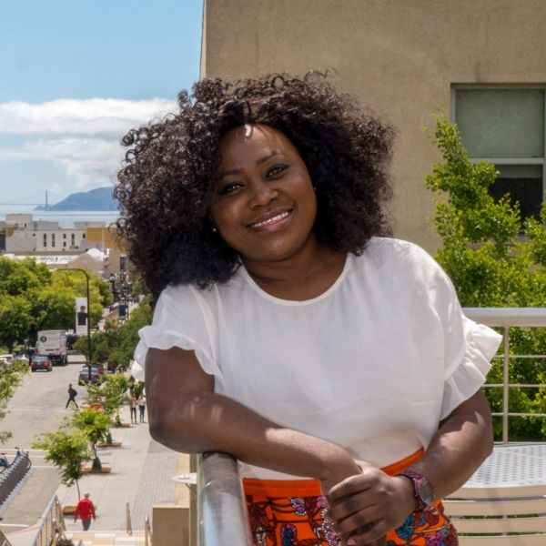 Smiling woman leaning on a railing outdoors.
