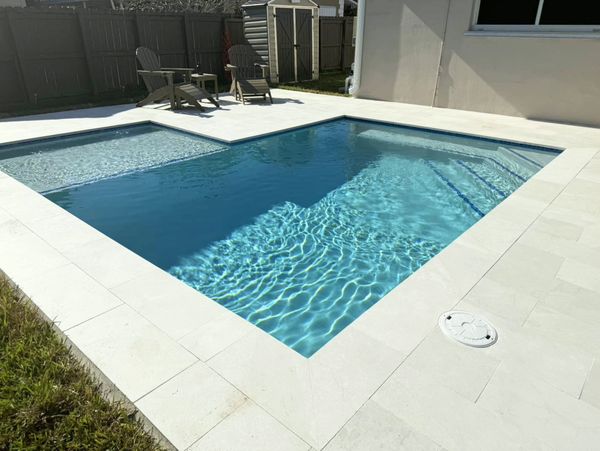 A modern backyard swimming pool with lounge chairs.