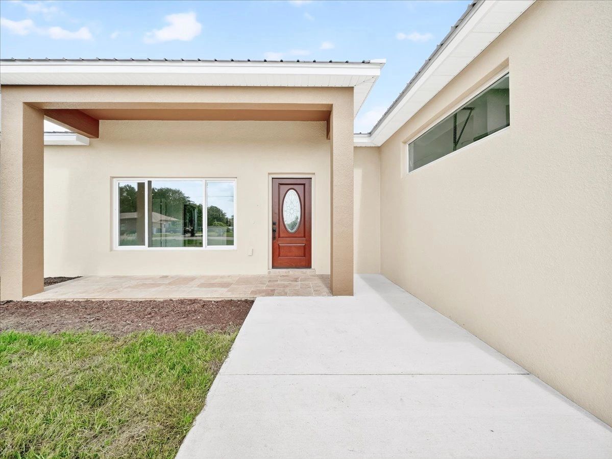 Modern beige house entrance with a wooden door and tiled porch.