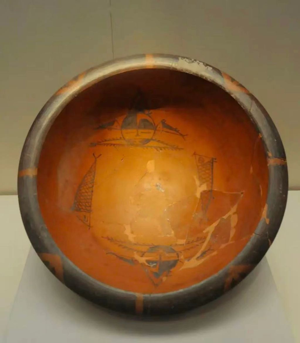 Ancient ceramic bowl with geometric and boat motifs, showing signs of age and restoration.