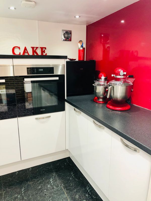 white kitchen units with 2 Miele ovens and candy red Kitchen Aid mixers