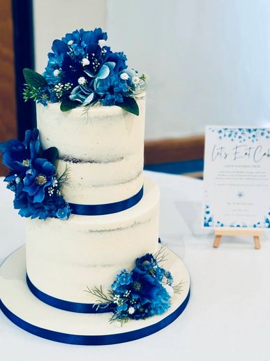 2 tier semi naked wedding cake with blue artificial flowers