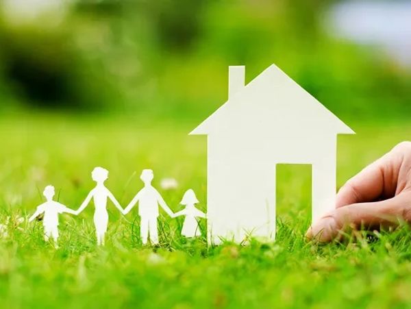 Paper cutout family and house on grass.