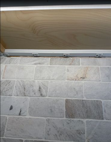 A under-cabinet outlet strip for countertop power without interrupting the stone backsplash.