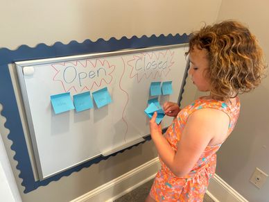Child organizing sticky notes on an open/closed board.