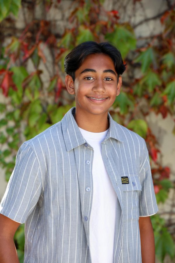 Teen boy smiling outdoors with fall foliage background.