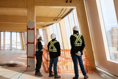 Three construction workers inspect a modern building interior under construction.
