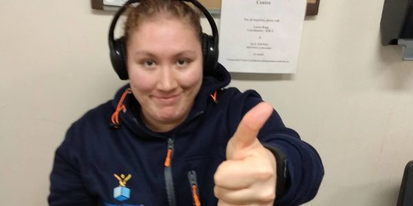 Glassbox Fitness Neurodivergent participant giving a thumbs-up while holding a phone and wearing headphones.