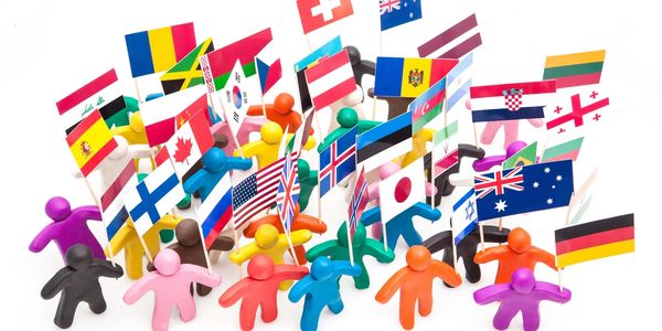 Colorful figurines holding various international flags symbolizing global unity and diversity.