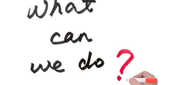 Hand writing "What can we do?" with a red question mark on whiteboard.