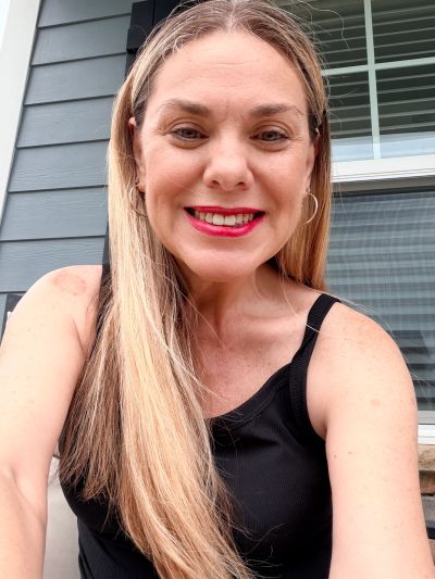 Smiling woman with long blonde hair and red lipstick.