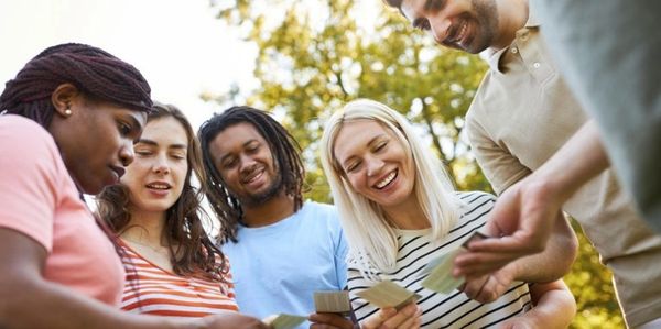A diverse group of friends happily playing cards outdoors.