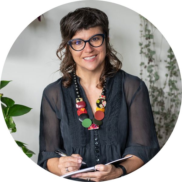 Leanne Levinge, Narrative Therapist, looks into the camera. She holds a notebook and pen.