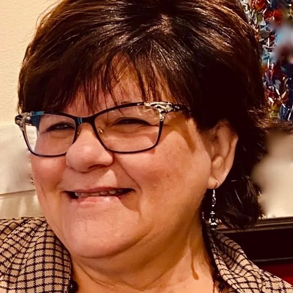Smiling woman wearing glasses and earrings.