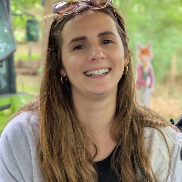 Smiling woman with long brown hair and sunglasses on her head outdoors.