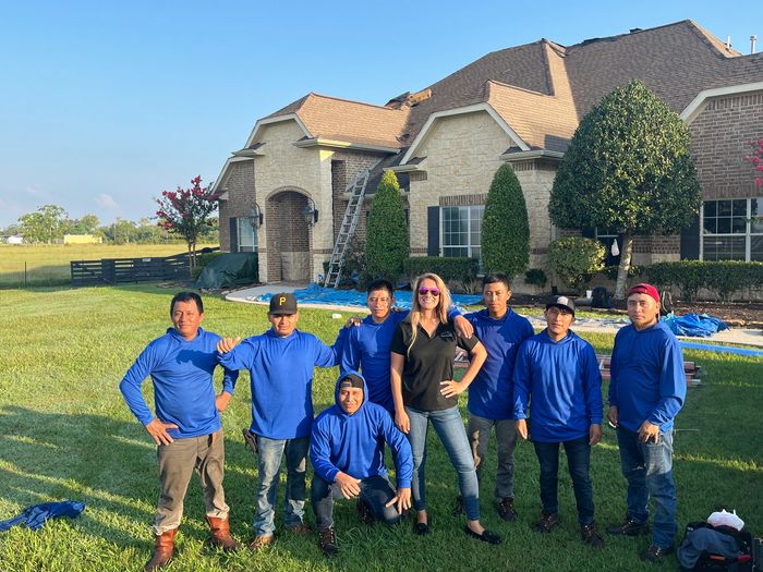 A group of workers posing in front of a house on a sunny day.
