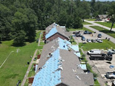A row of houses with blue tarps covering damaged roofs amid repair work.