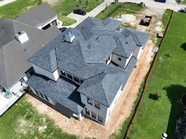 A large, multi-gabled house under construction with new roofing.