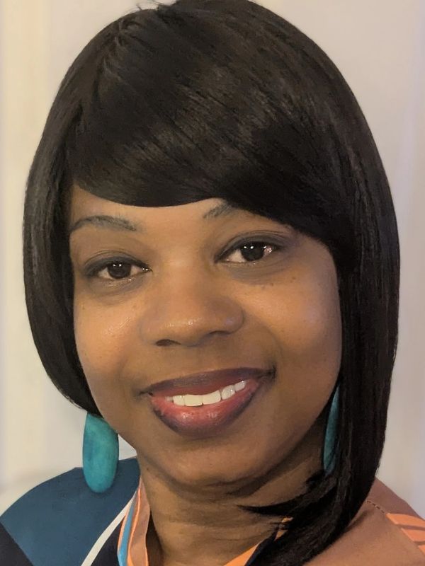 Smiling woman with sleek black hair and turquoise earrings.