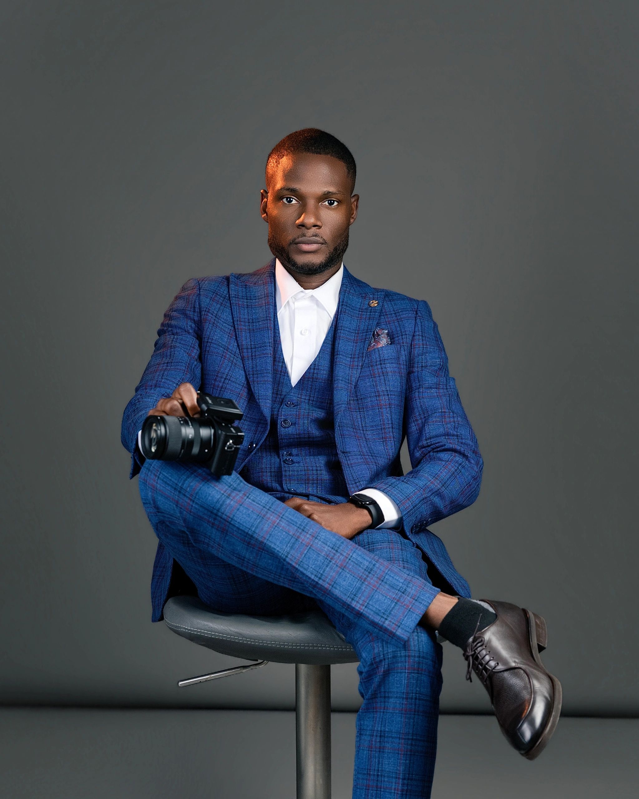 Man in blue suit holding a camera.