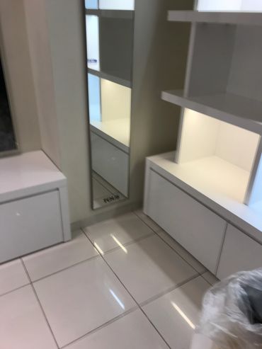 Modern white furniture with shelves and a mirror in a clean room.