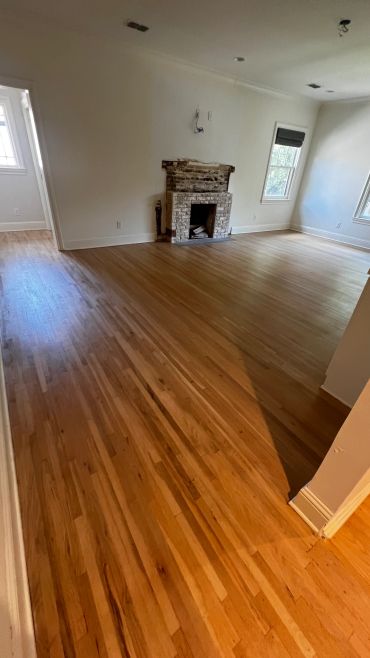Empty room with unfinished fireplace and hardwood floor.