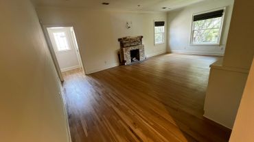 Empty room with hardwood floors and a small fireplace.