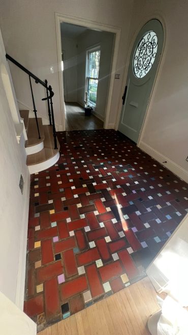Entryway with patterned brick floor and a green door.