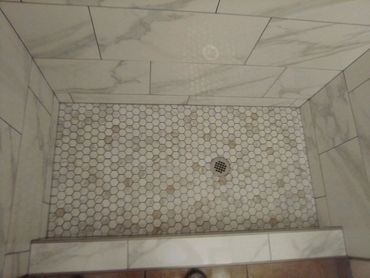 Shower pan with mosaic Carrera tile and 12 x 24 wall tiles.