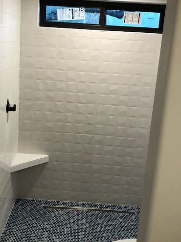 Custom shower with floating bench and mosaic shower pan with an infinity drain