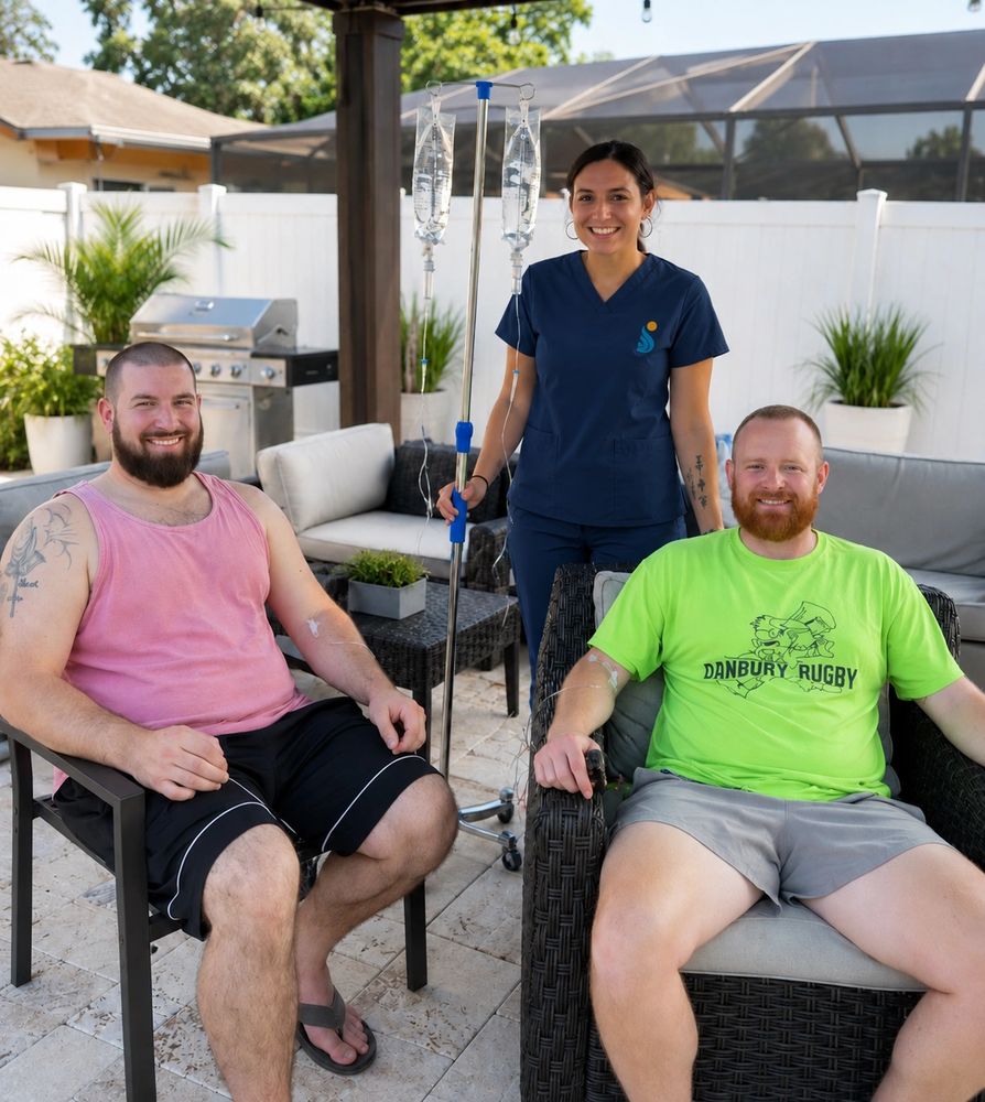 Two men sitting outdoors with a nurse holding IV bags.