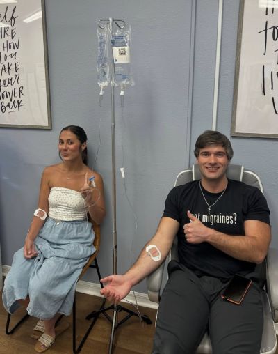Two people receiving IV therapy and smiling.