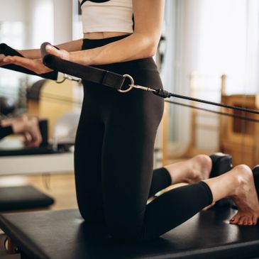 Person exercising on Pilates reformer machine focusing on core strength.
