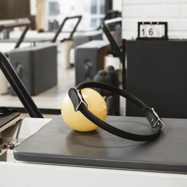 Pilates ring and yellow ball on exercise machine in a gym.