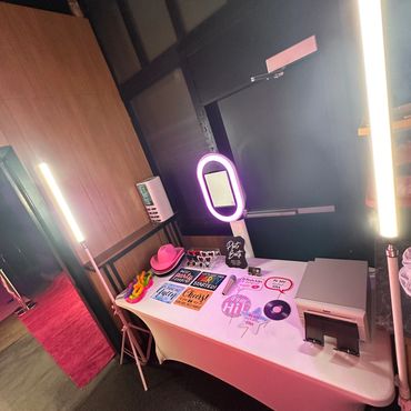A photo booth setup with props, lights, and a printer on a white table.