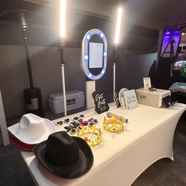 Photo booth setup with hats, crowns, and props on a white table.