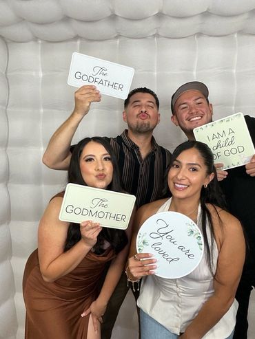Four friends posing with signs: The Godfather, The Godmother, I am a child of God, and You are loved.