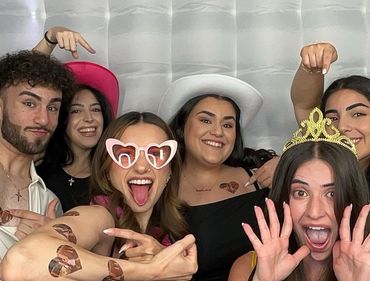 Group of friends having fun with heart-themed stickers and party accessories.