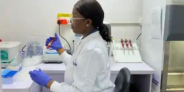 Scientist in a lab coat using a pipette in a laboratory.