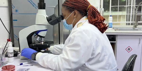 Scientist in a lab coat examines samples using a microscope in a laboratory.