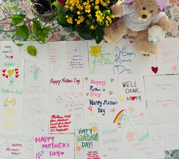 Handmade colorful Mother's Day cards arranged with flowers and teddy bears.