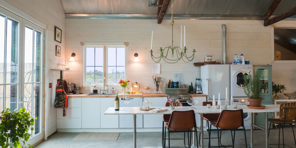 Bright kitchen with white cabinets and brown chairs.