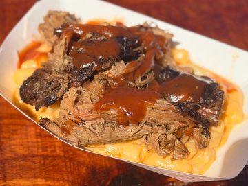 Barbecue brisket with sauce over macaroni and cheese.