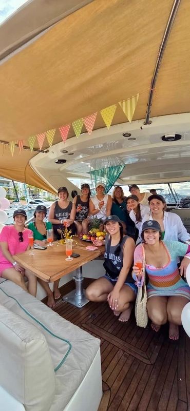 Group of women enjoying a party on a boat with drinks and decorations.