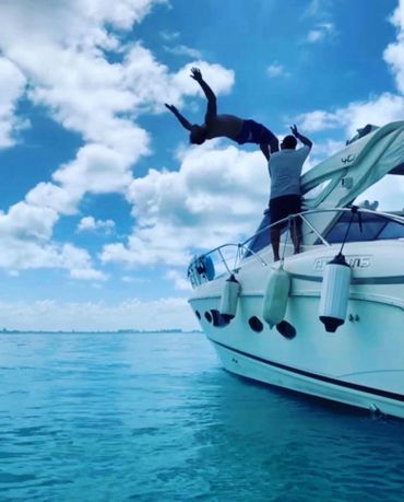 Person flipping off a boat into the water on a sunny day.