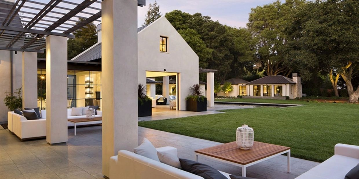 Modern outdoor seating area with white sofas and wooden table.