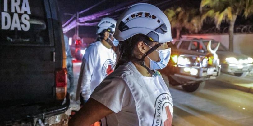 Two rescue workers wearing helmets and masks at night.