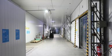 Pasillo de almacenamiento industrial con equipo y carrito.