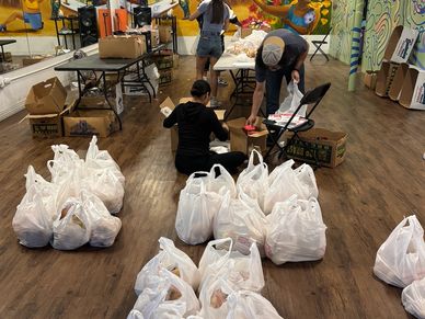 People packing food grocery bags with food in a classroom